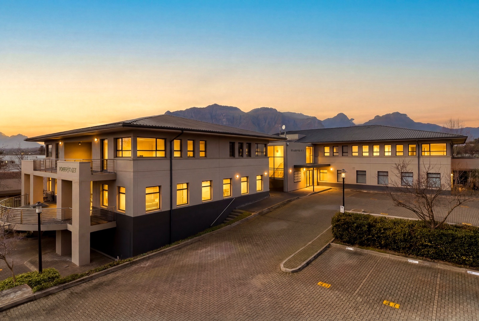 Block 2 at Blaauwklip Office Park at dusk, windows lit, with the mountains behind