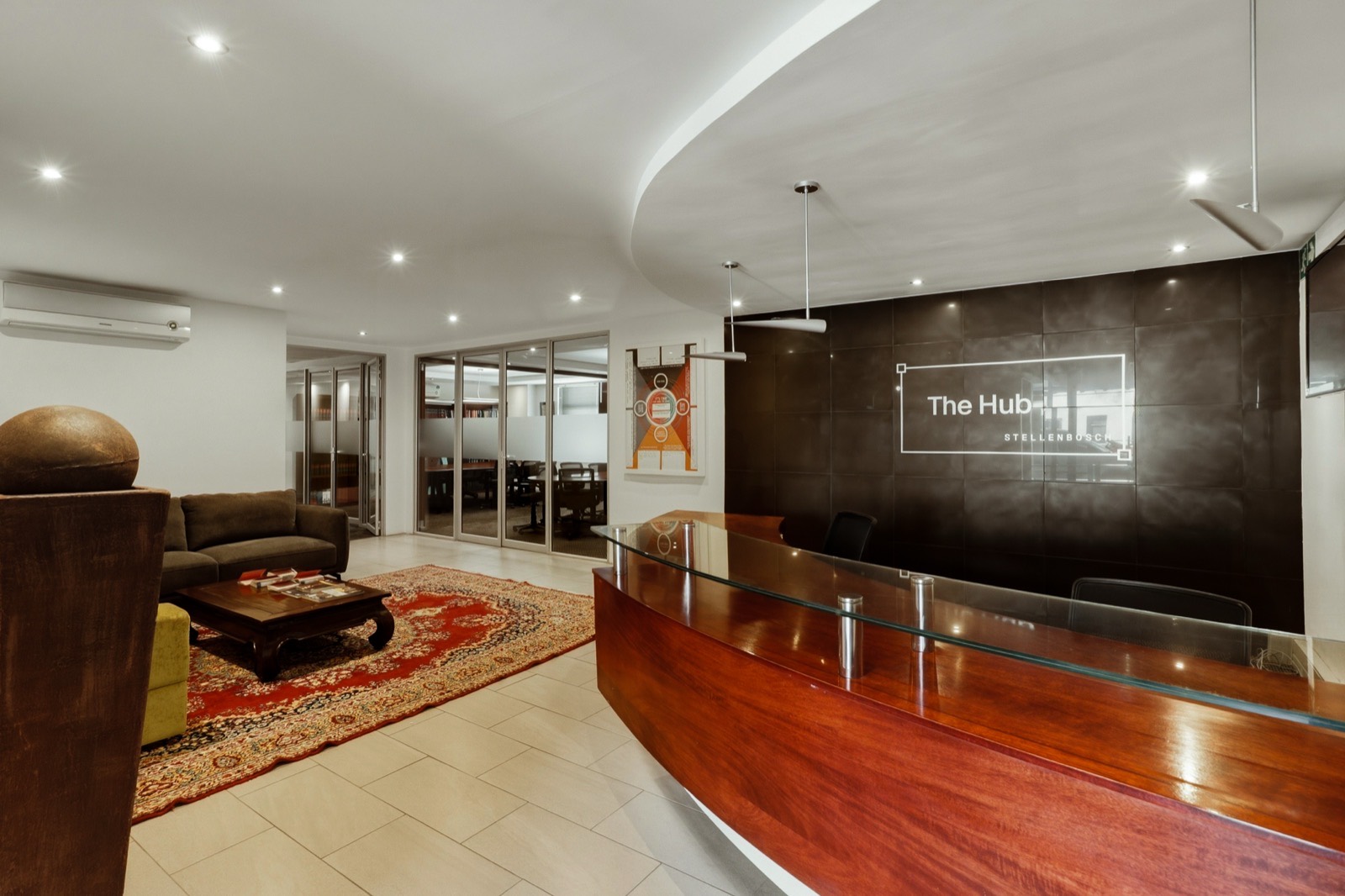 Reception at The Hub, with the curved timber desk and The Hub sign on the dark feature wall